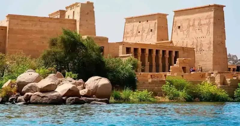Piloni del Tempio di Philae tra rocce e alberi in riva all'acqua