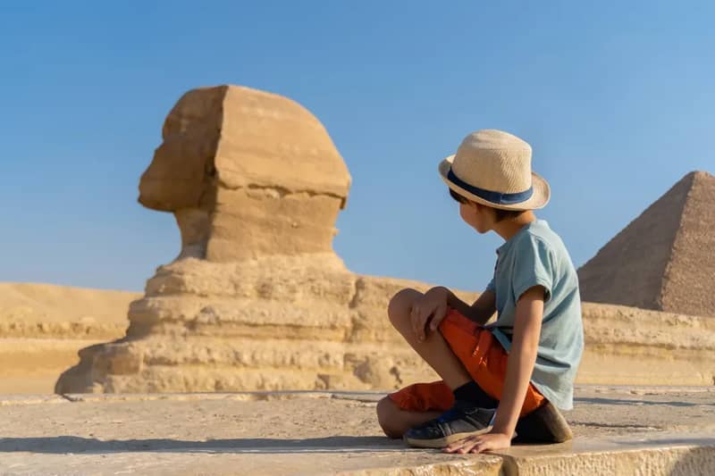 Giovane viaggiatore seduto accanto alla Sfinge di Giza