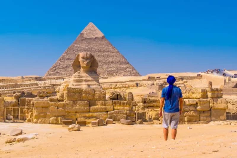 Mann vor der Großen Sphinx von Gizeh und einer Pyramide