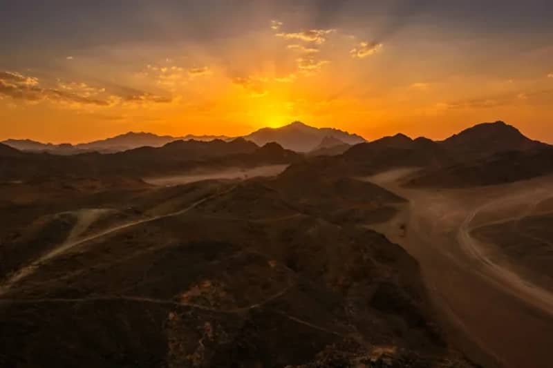 Coucher de soleil orangé sur des montagnes désertiques
