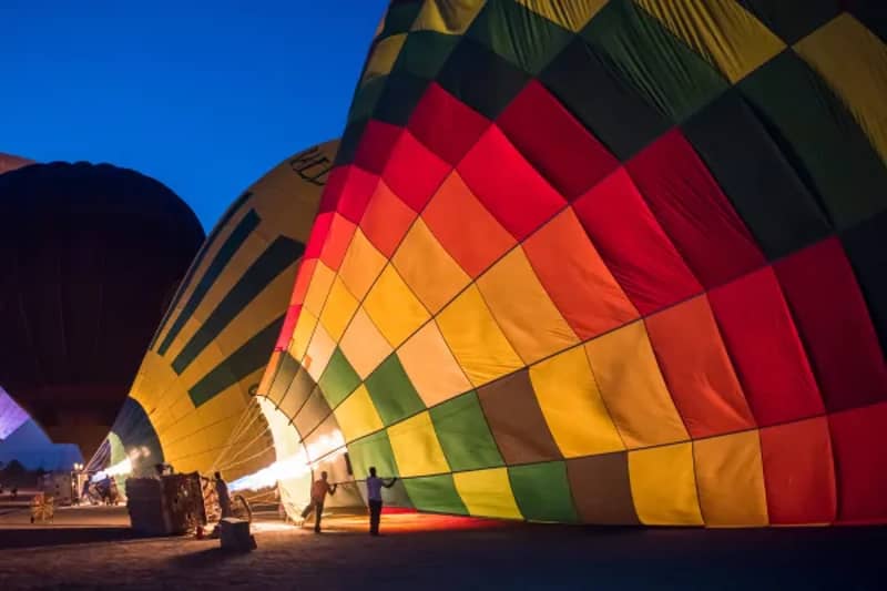 Bunter Heißluftballon wird vor einer Fahrt im Morgengrauen in Luxor befüllt