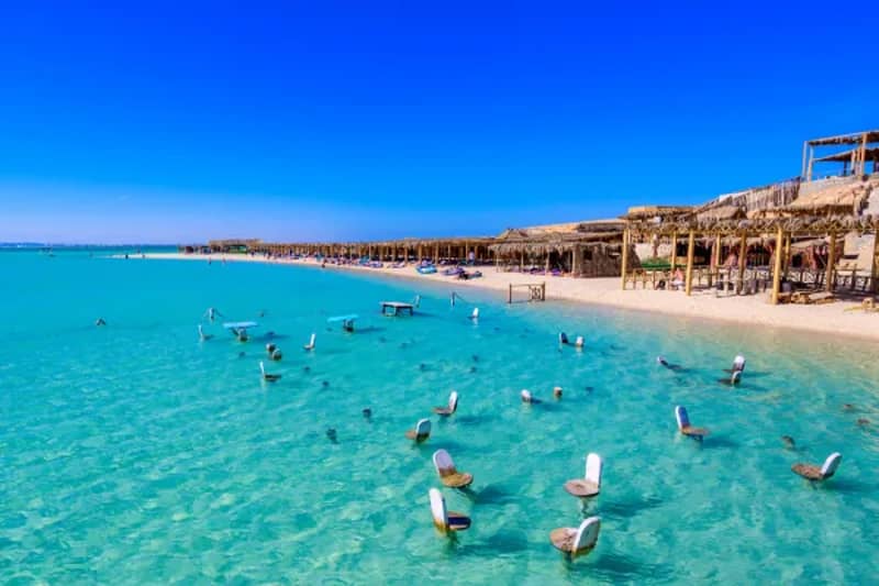 Flaches türkisfarbenes Wasser und Strand mit Hütten in der Orange Bay