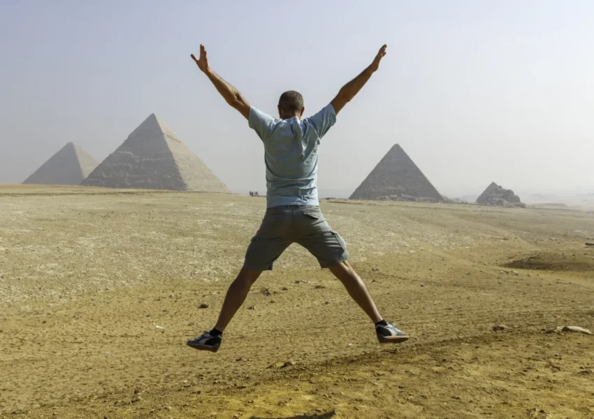 Person celebrating in front of Egyptian Pyramids.